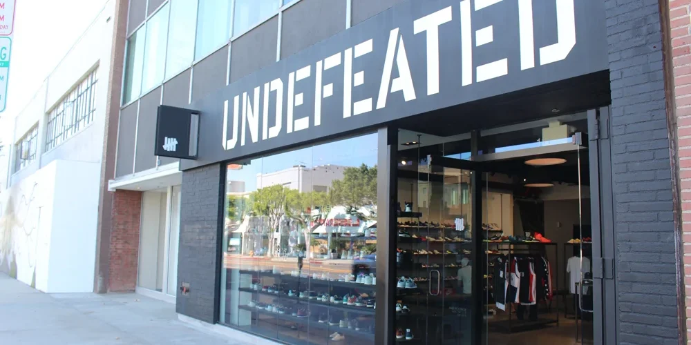 Fachada de Undefeated en La Brea Avenue, Los Ángeles, con grandes letras blancas sobre la entrada de vidrio.