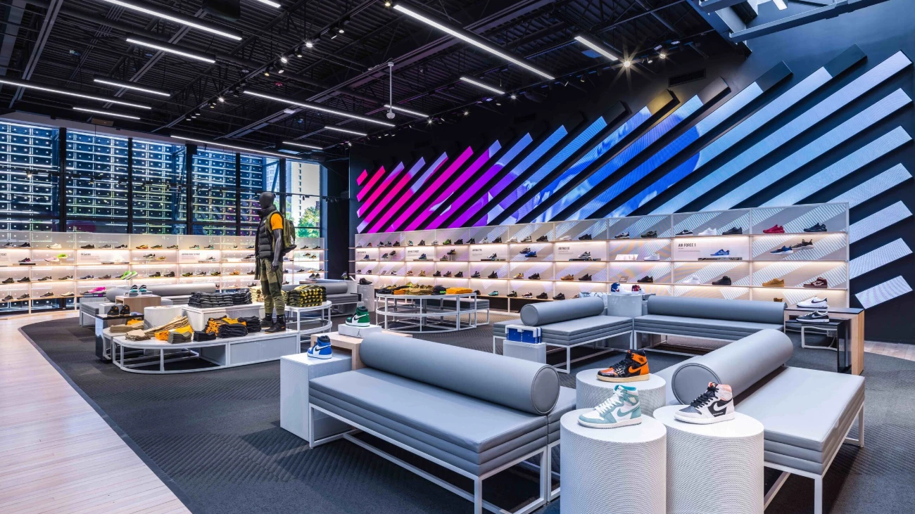 Nike sneaker department with illuminated walls, gray seating and colorful diagonal panels.