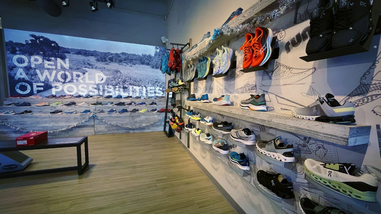 Running-shoe walls around a bench beneath a large landscape graphic and slogan.