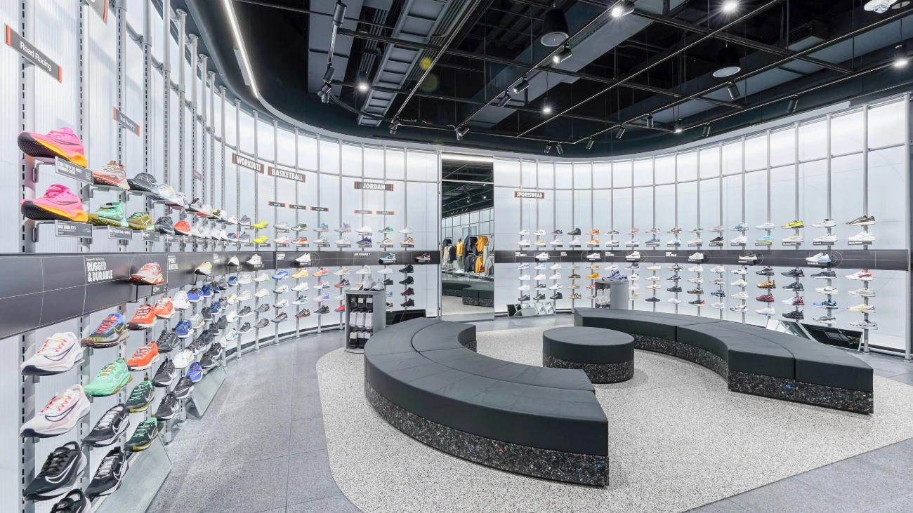 Curved sneaker-display area with dark benches and illuminated white walls
