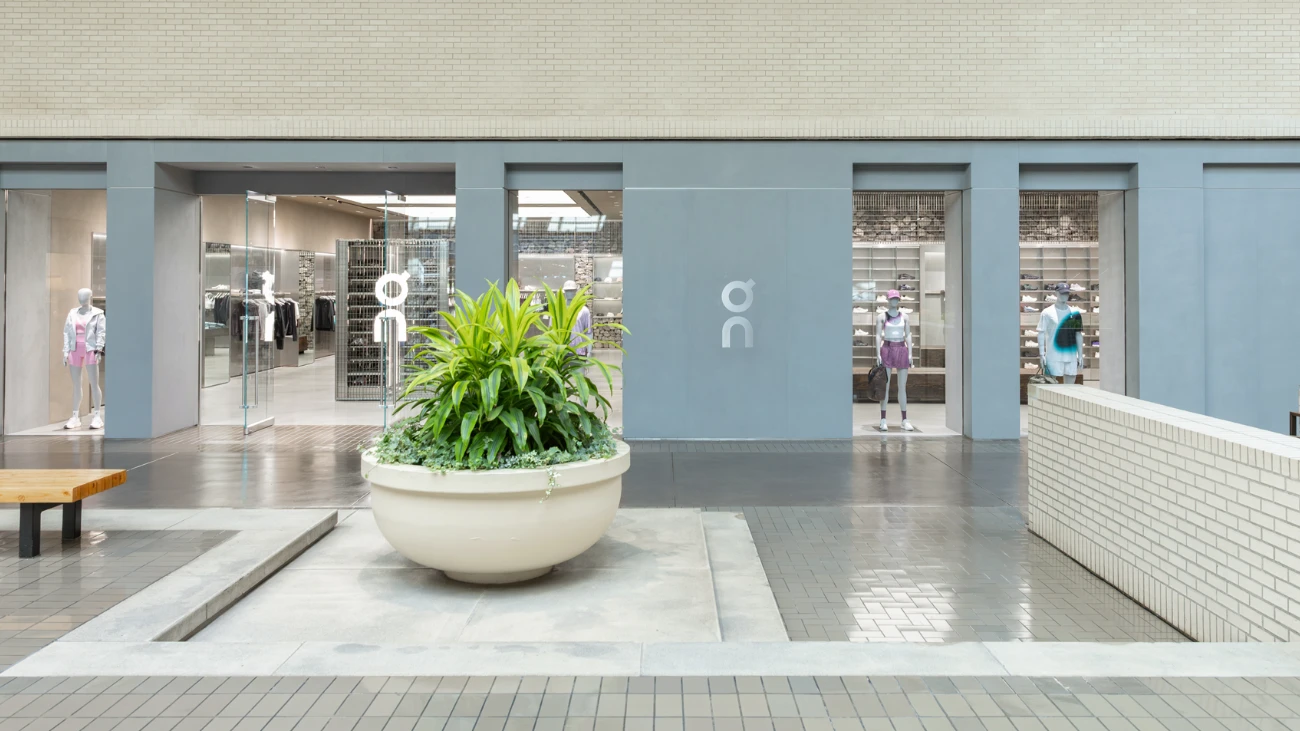 On storefront with pale walls, glass entrances and a central planter