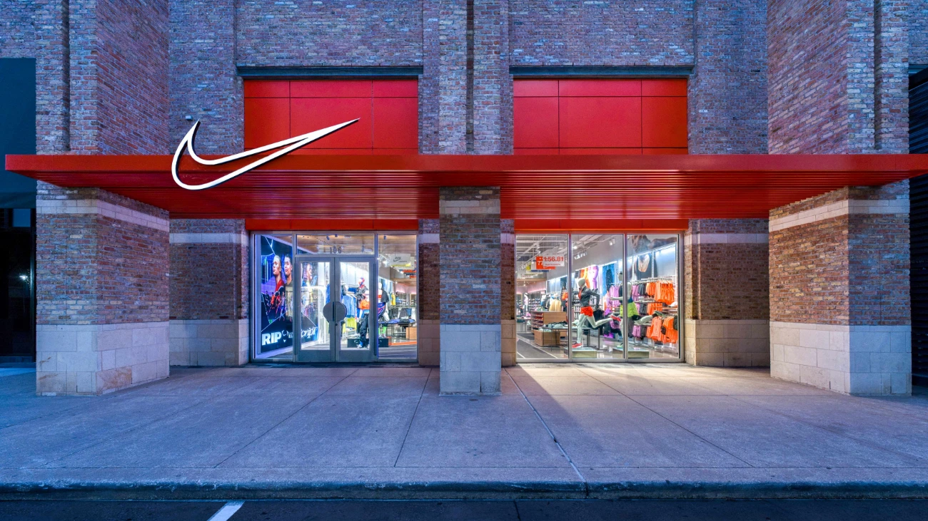 Nike storefront at dusk with red architectural panels and bright windows