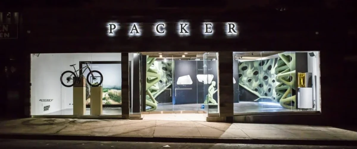 Lapstone & Hammer interior in Philadelphia, with illuminated sneaker shelves, seating and a curved mezzanine above.