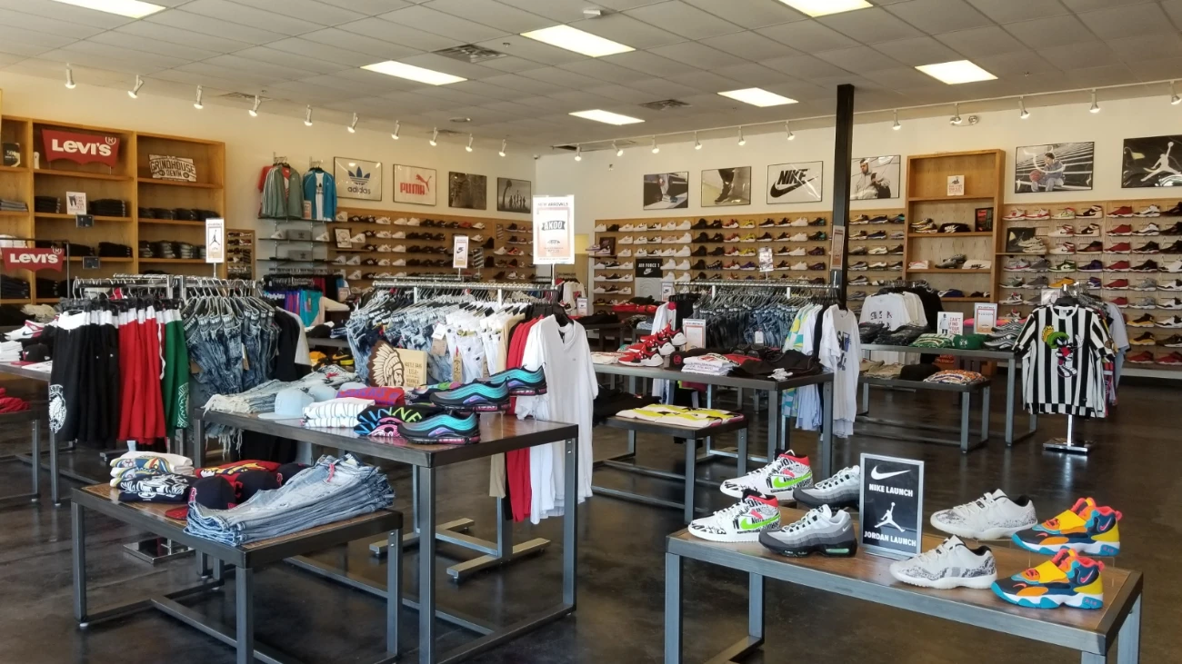 Store overview with central sneaker tables and clothing racks