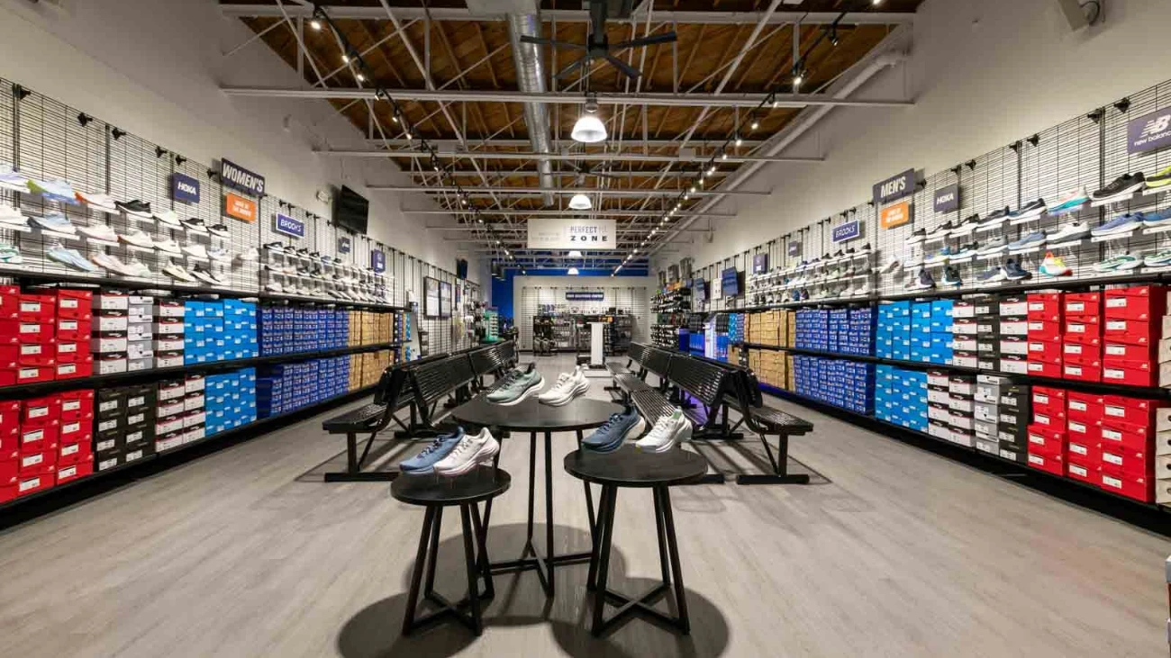Spacious running store with shoe walls, stacks of colorful boxes and central fitting benches.