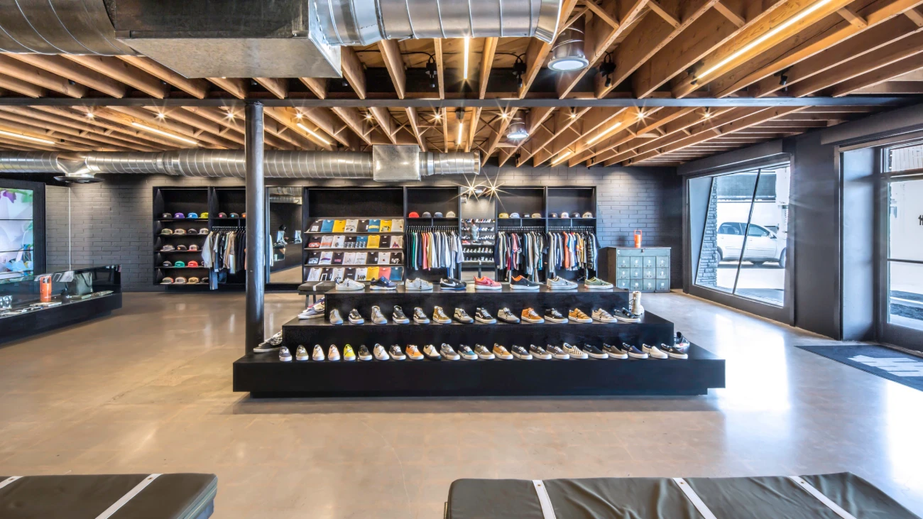 Spacious sneaker boutique with exposed wooden beams and a central tiered shoe display.