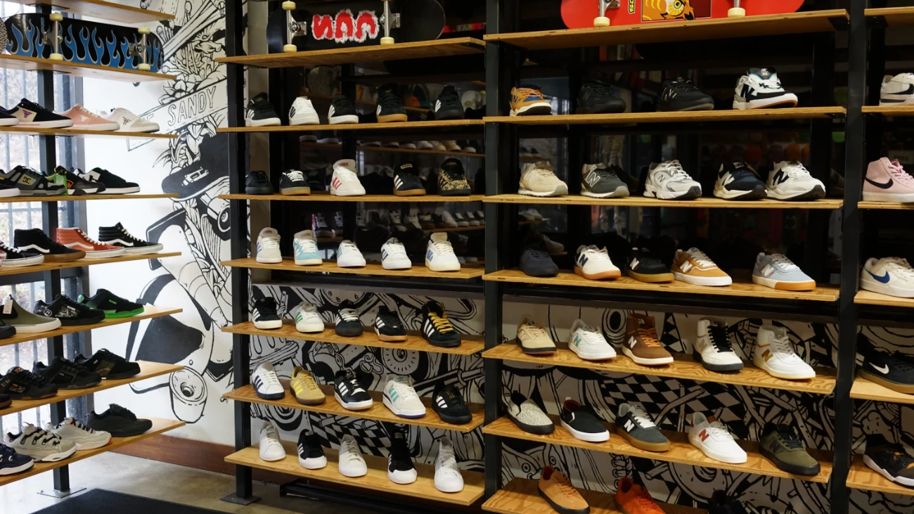 Skate shoes arranged in wooden cubbies against graphic wallpaper.