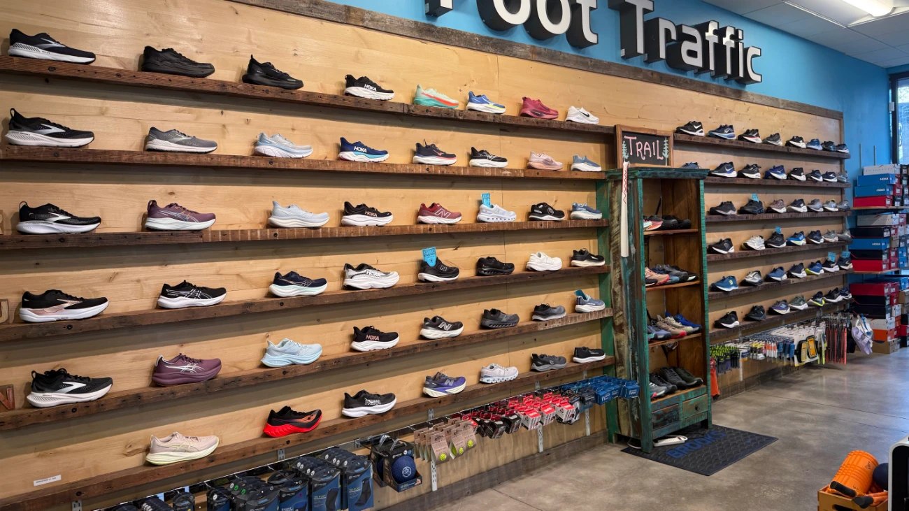 Foot Traffic running-shoe wall with long wooden shelves and a full-length mirror.