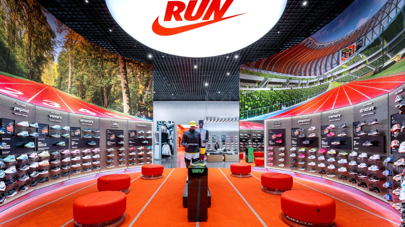 Nike running department with a red track-pattern floor, shoe walls and round red seats.