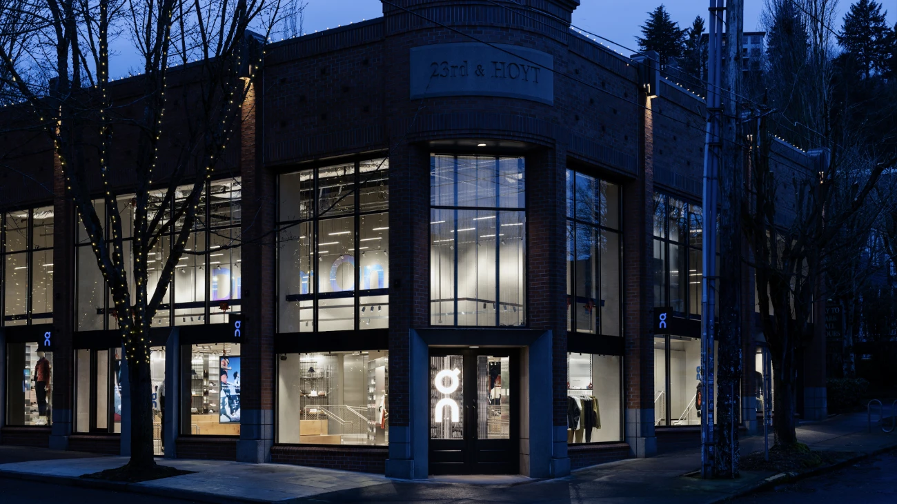 Two-story On storefront at dusk with tall illuminated windows.
