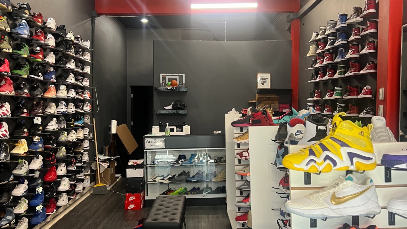 Compact sneaker shop with densely packed shoe walls, display cases and a fitting bench.