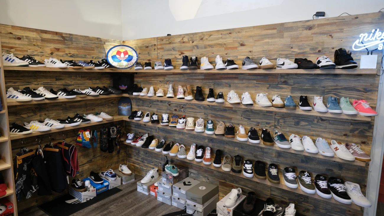Sneakers arranged on rustic wooden walls above stacks of shoeboxes.