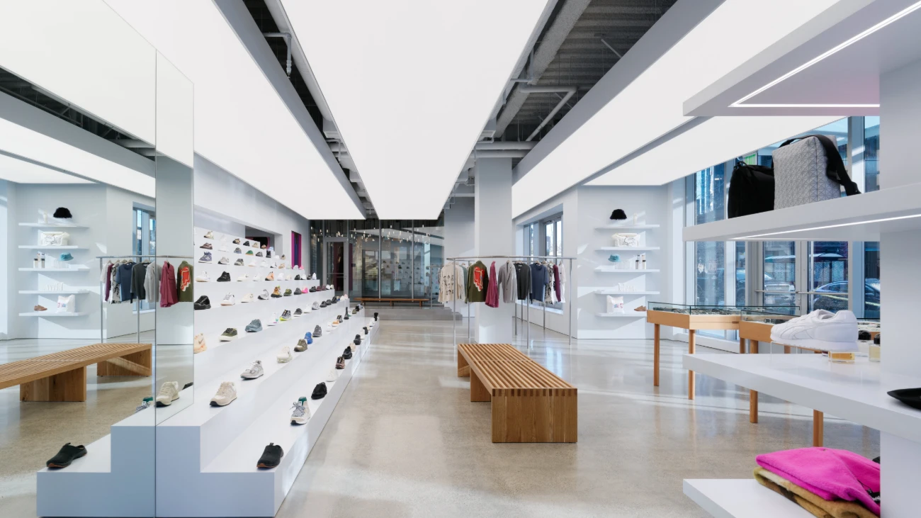 Minimalist sneaker boutique with angular white ceilings, shoe displays and wooden benches.