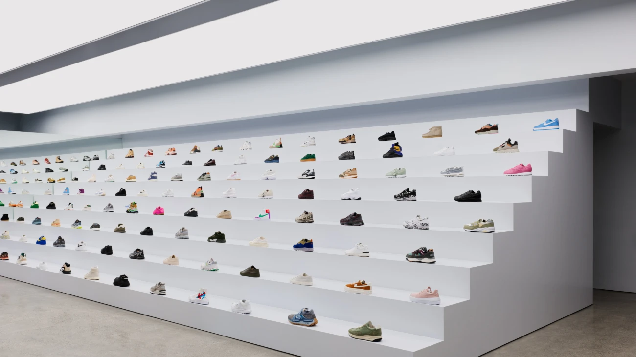 Long stepped white display filled with sneakers inside a minimalist boutique.