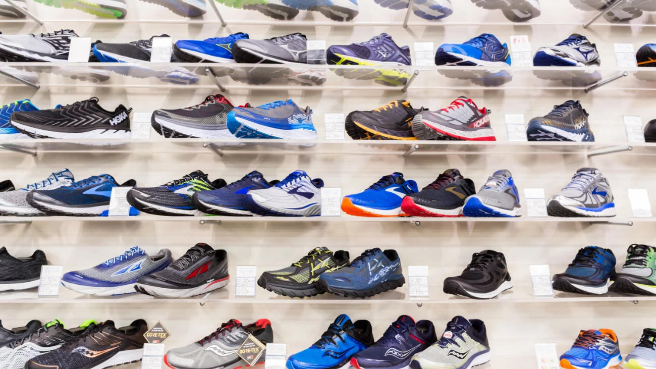 Rows of multicolored running shoes on a white wall display.